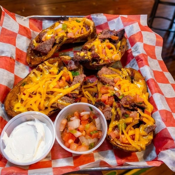 Four loaded potato skins with steak, cheese, and pico de gallo, served with sour cream.