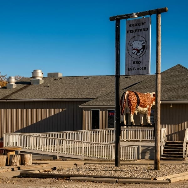 Smokin' Hereford BBQ restaurant exterior with a large bull statue, sign, and outdoor seating.
