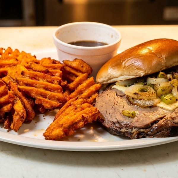 Roast beef sandwich with melted cheese, grilled onions, and peppers, served with waffle fries and au jus.